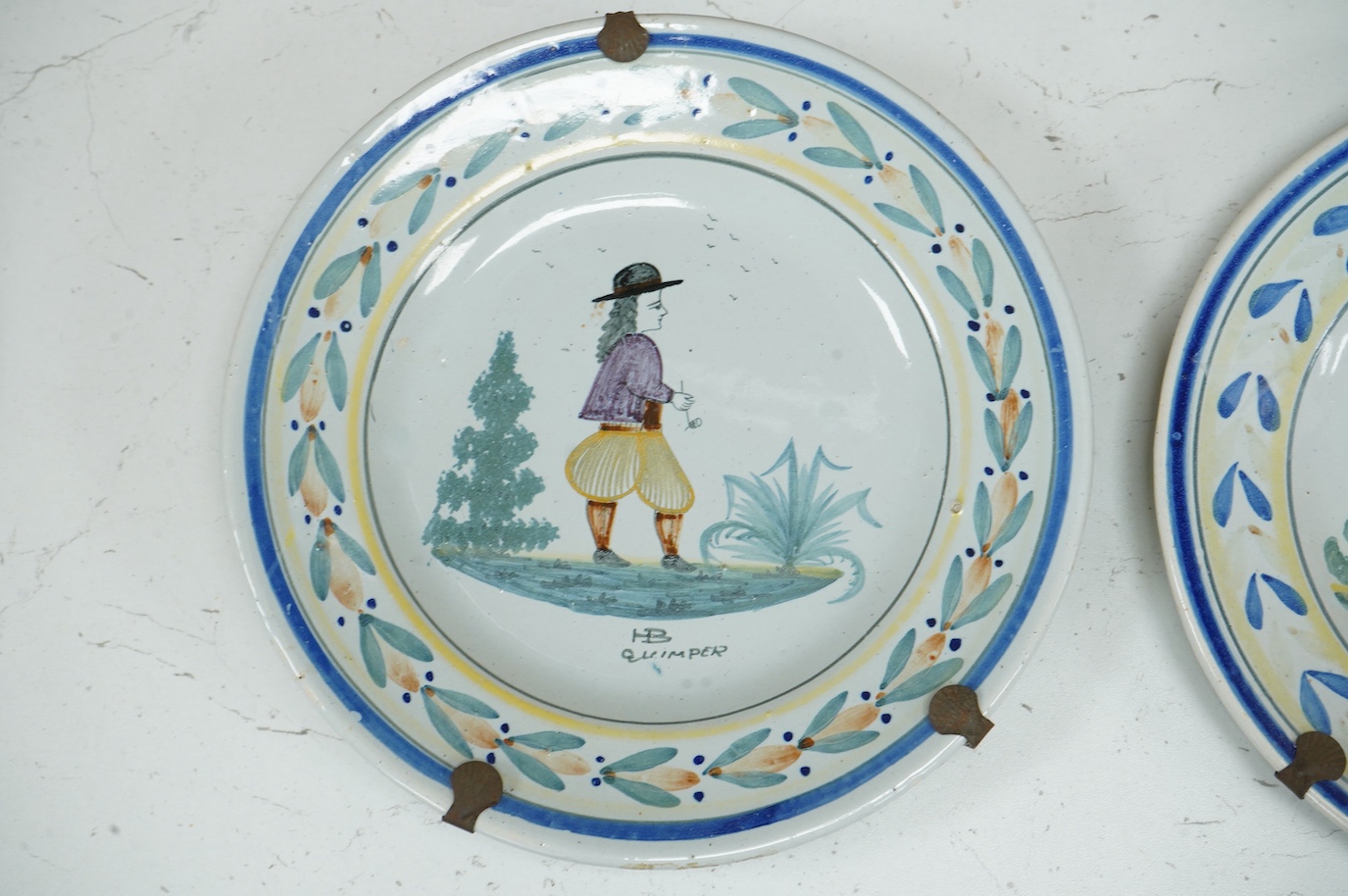 Four Quimper faience plates, each signed to the bases, 23cm in diameter